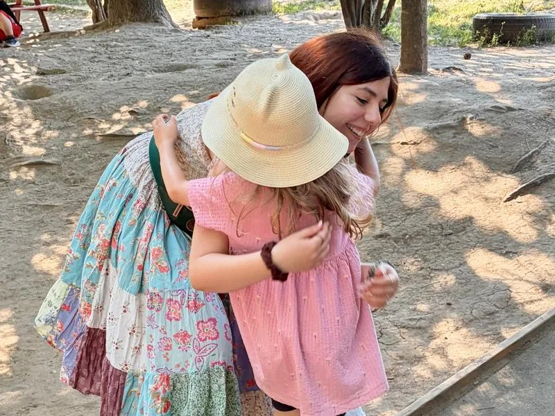 Mamă îmbrățișându-și copilul în grădina Arcadia Montessori, în perioada de acomodare