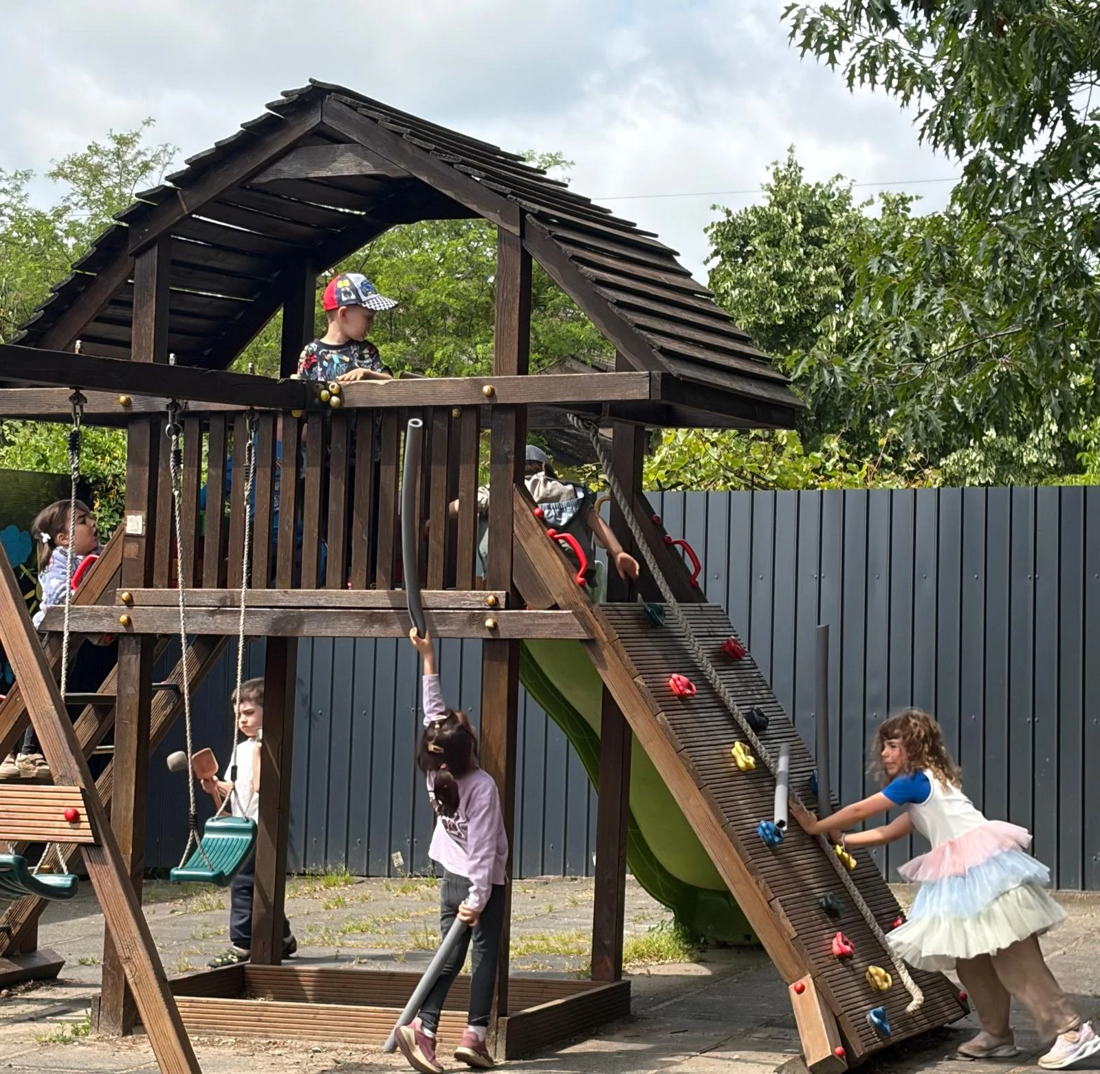 Copii jucându-se pe ansamblul de cățărare din grădina Arcadia Montessori, Corbeanca